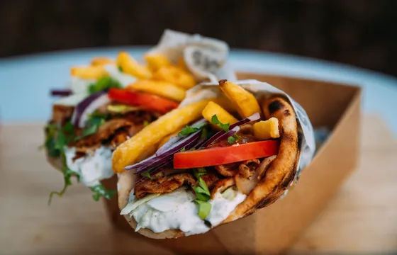 Fläskkarré gyro i pita med pommes, tomat, rödlök och tzatziki i en kartongbox