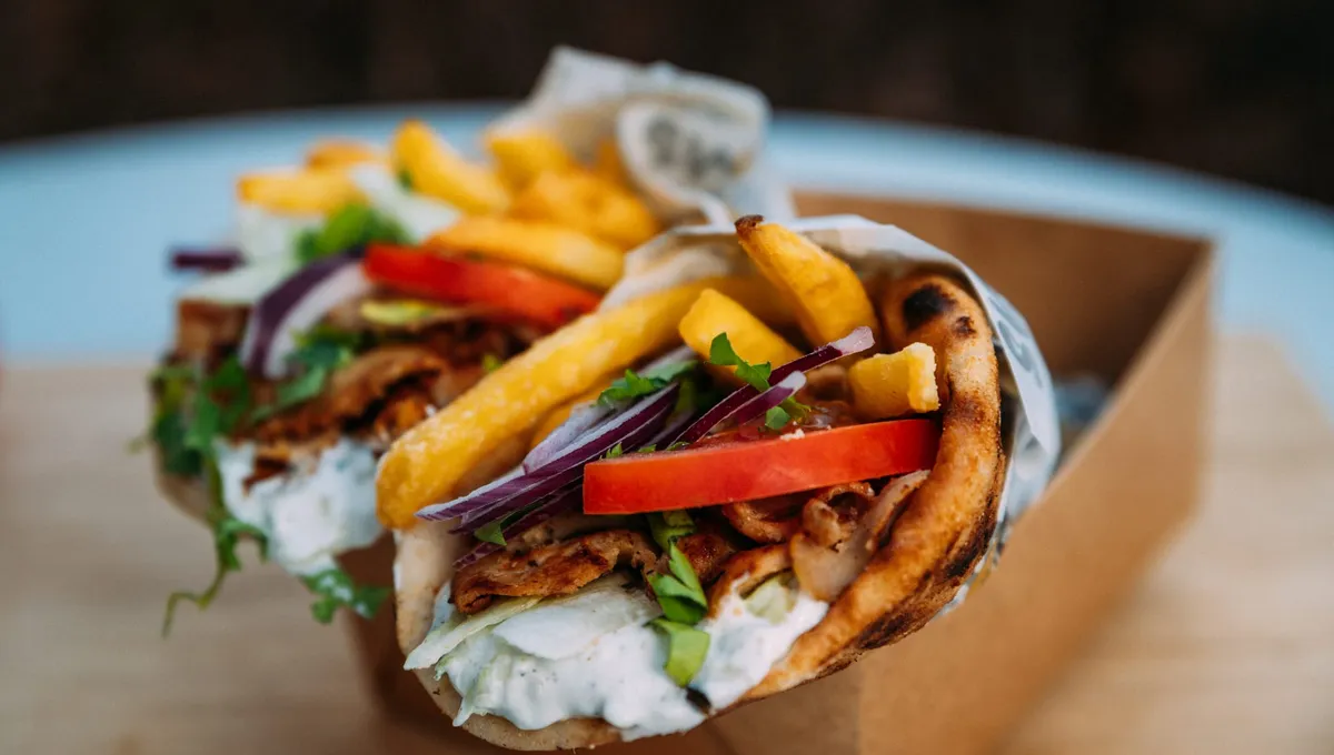 Fläskkarré gyro i pita med pommes, tomat, rödlök och tzatziki i en kartongbox